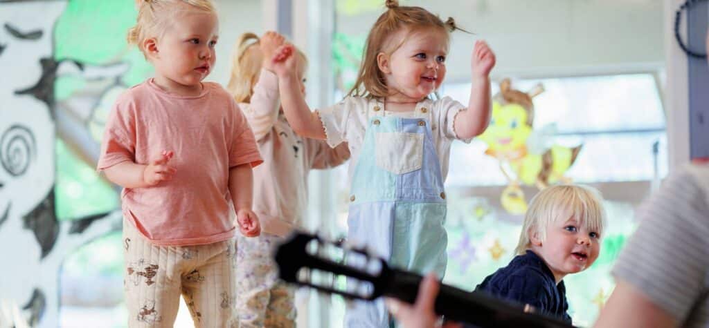 tre barn som danser til gitar i en barnehage