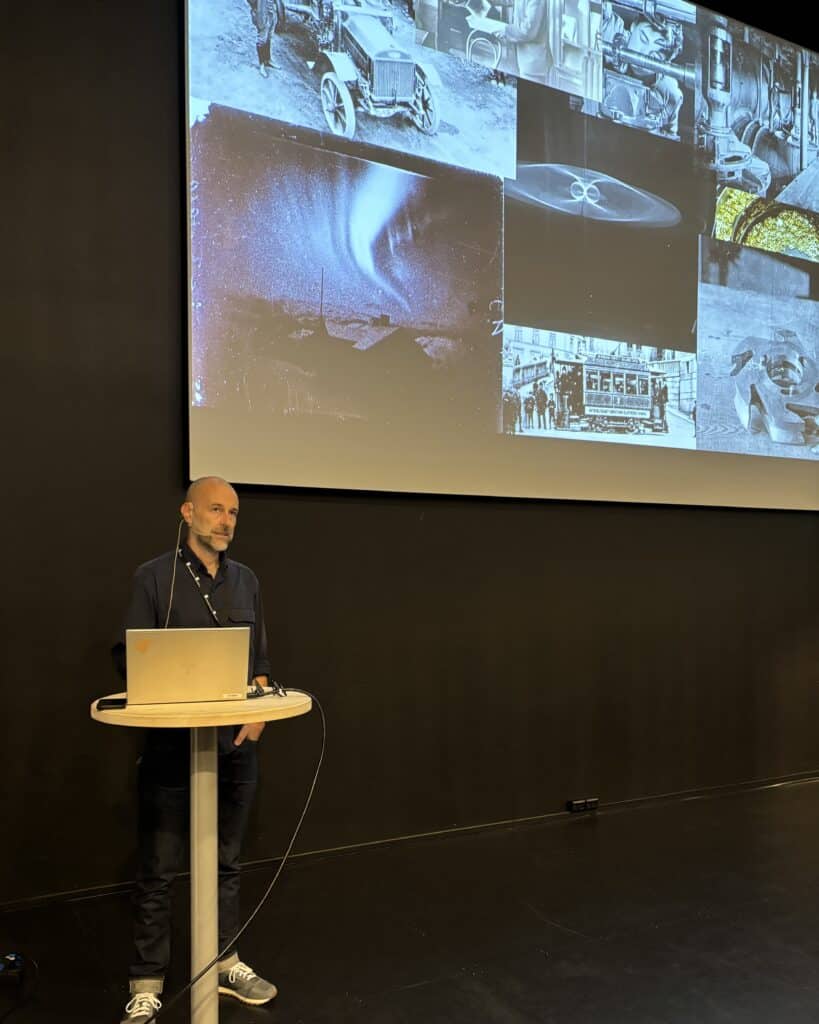 foredragsholder med bilde fra presentasjon i bakgrunnen