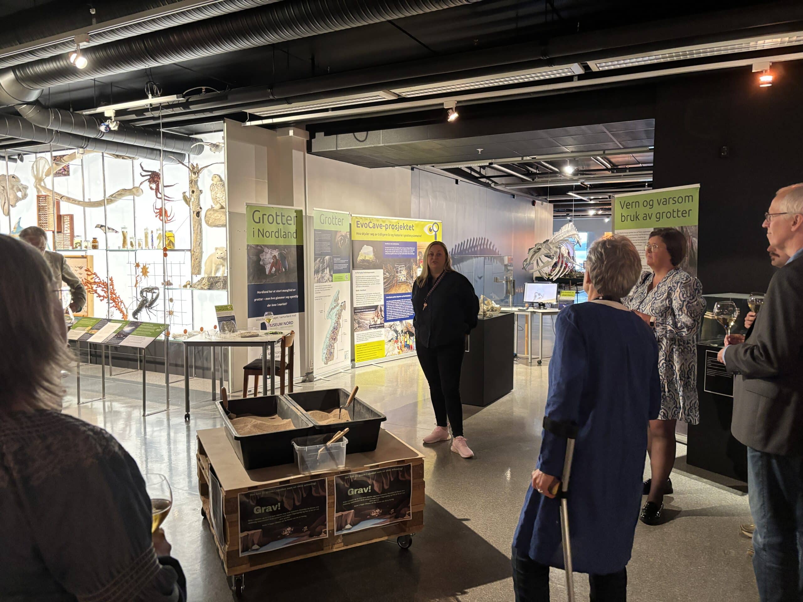 Omviser ved museum snakker til folk som står rundt.