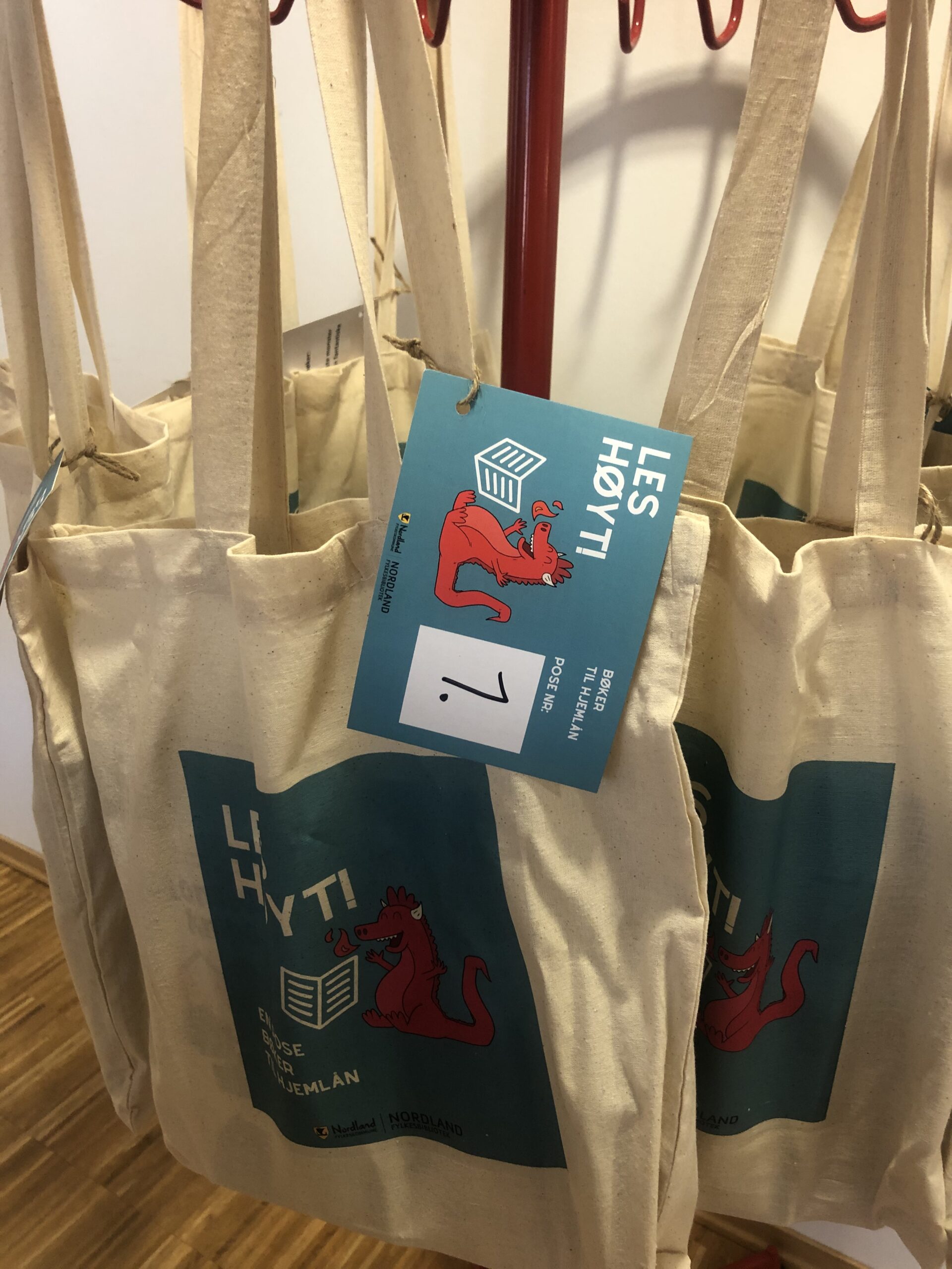 Flere tøyvesker med merkelapp Les høyt! som henger klare til utlån i barnehagen.
