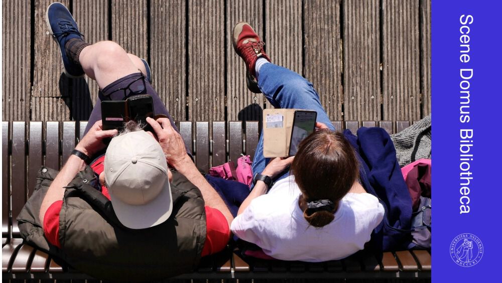 To personer sitter på en benk. Ser på telefon. Sett ovenfra.